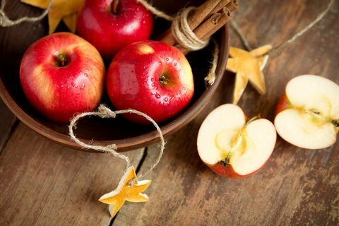 Rijpe verse rode appels in kom met kaneel op houten achtergrond. Herfst oogst. kerst decoratie