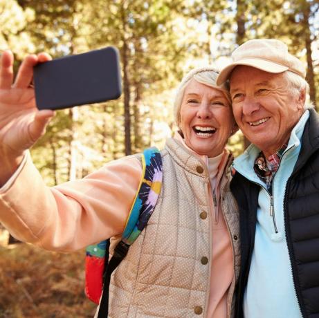 Senior koppel op wandeling in een bos dat een selfie maakt