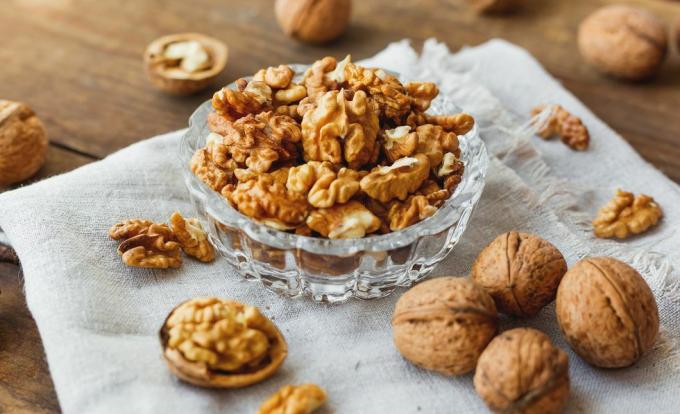 Glazen kom met walnoten op rustieke handgeweven servet. Gezonde snack.