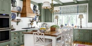 keuken met rustgevende groen geschilderde kasten, spanten en sierlijsten gecombineerd met witte lambrisering, plafond en eiland