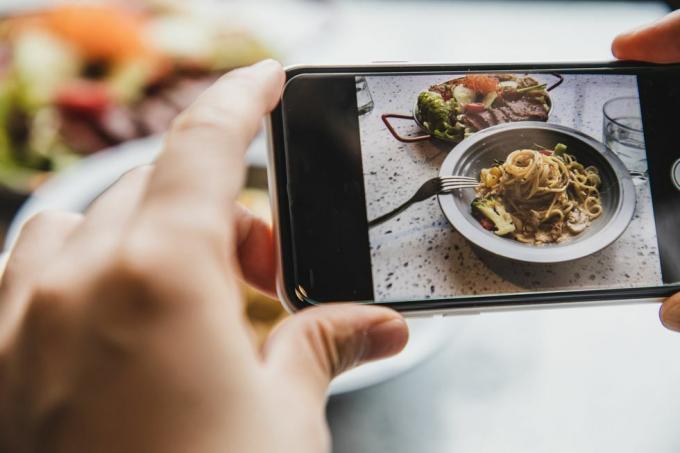 persoonlijk perspectief van het gebruik van de telefoon om een ​​foto te maken van romige spekspaghetti en salade