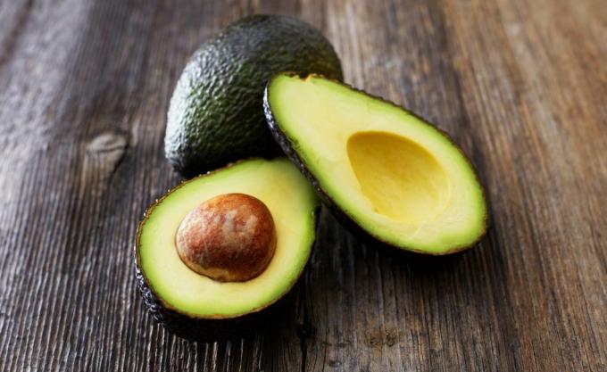 Hele en gesneden avocado op hout