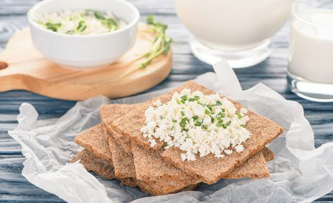 vergrote weergave van krokante crackers met topping van cottage cheese op houten tafel