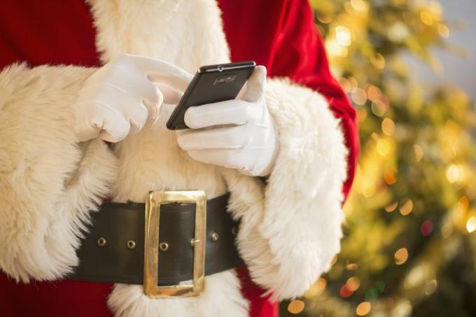 De Kerstman houdt mobiele telefoon vast