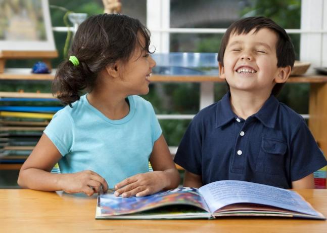 twee lachende kinderen genieten van een boek op school