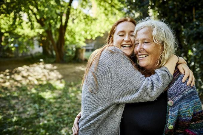 gelukkige aanhankelijke oudere vrouw en jonge vrouw in de tuin