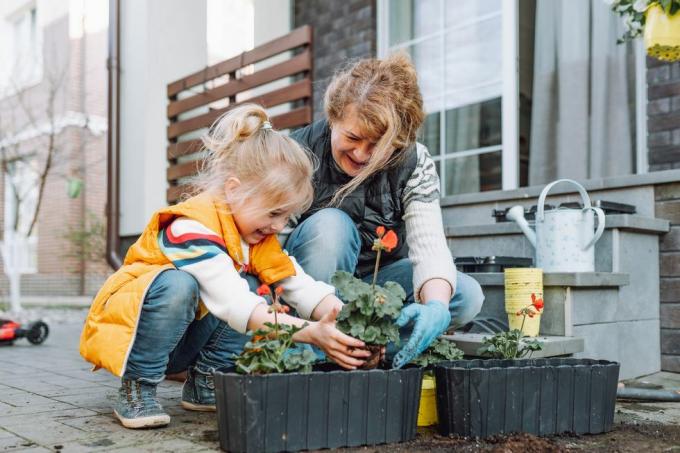 oma met kleine kleindochter bloemen oppotten op een veranda in het voorjaar