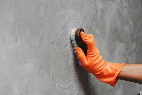 Bebouwde Hand van de mens die grijze muur schoonmaken