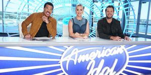 Lionel Richie, Katy Perry en Luke Bryan zitten aan een bureau met het American Idol-logo op de voorkant