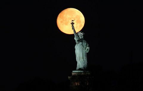 De maan gaat onder achter het Vrijheidsbeeld in New York City