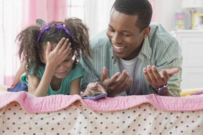 vader en dochter gebruiken mobiele telefoon samen op bed