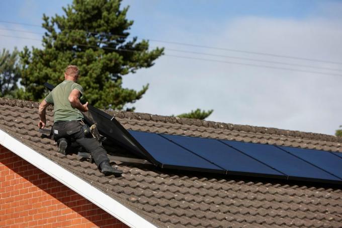 h0chn1 man die zonnepanelen op het dak installeert in een huishoudelijke zonnepaneelinstallatie in Groot-Brittannië