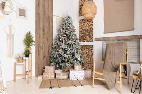 ingericht kerst woonkamer interieur met prachtige dennenboom geschenkdozen op de vloer, brandhout voor een open haard