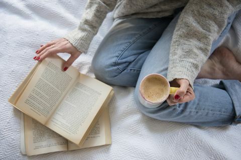 Vrouw in bed met koffie en boek