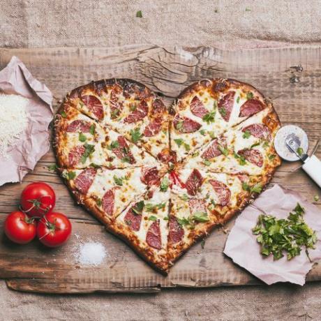 hartvormige pizza en ingrediënten op snijplank