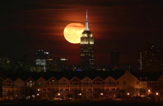Volle maan komt op achter het Empire State Building in New York City
