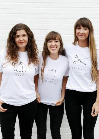 drie vrouwen in witte t-shirts, met steen, papier of schaar geschreven en afgebeeld op het shirt
