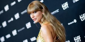 Taylor Swift kijkt over de schouder op rode loper in gouden jurk