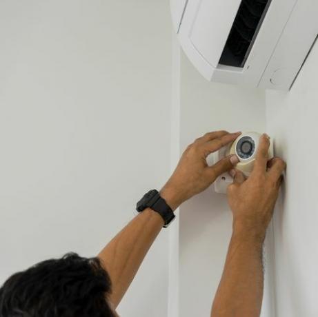 bijgesneden hand man cctv installeren op de muur thuis