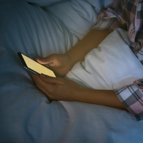 vrouw die 's nachts smartphone in bed gebruikt, close-up nomofobie en slaapstoornisprobleem
