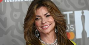 shania twain in gele jurk en diamanten halsketting