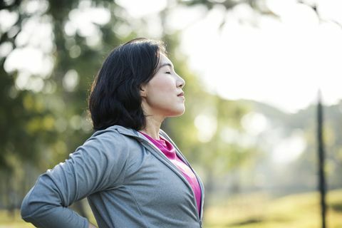 rust en herstel na het sporten zijaanzicht van aziatische werkende vrouwen rusten uit na buiten trainen in een stadspark