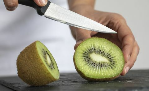 een vrouw die kiwi snijdt