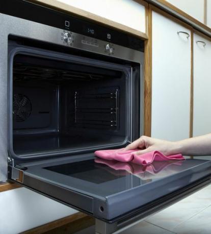 Vrouwen die de oven met handdoek schoonmaken