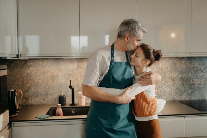 volwassen man met zijn tienerdochter omarmen in de keuken