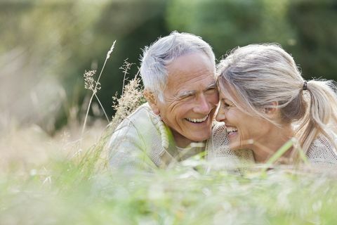 Gelukkige bejaarde paarzitting in lang gras