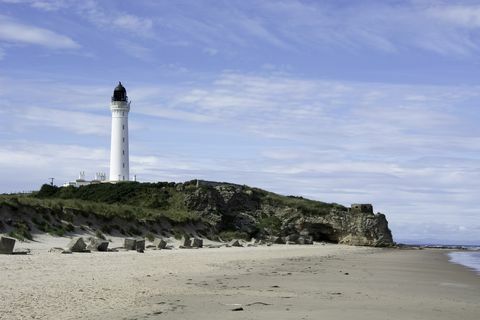 Kustscène met vuurtoren en zeegrotten