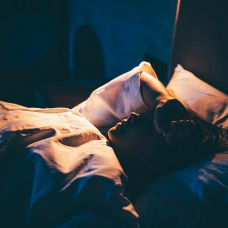 vrouw met slapeloosheid jonge vrouw liggend op bed met de hand op het voorhoofd