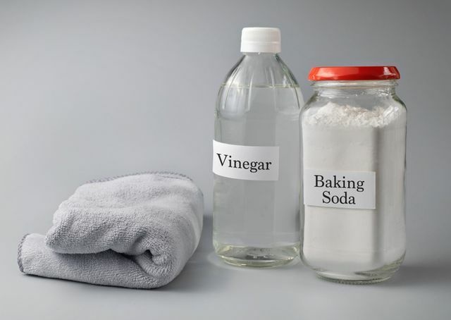 close-up van azijn en zuiveringszout tekst op glazen fles tegen grijze achtergrond