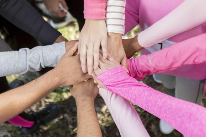 kring van mensen die roze shirts dragen met hun handen in eenheid samen