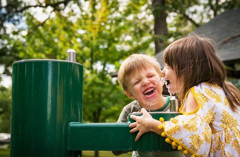 Twee kinderen die van een foto van de waterfontein drinken