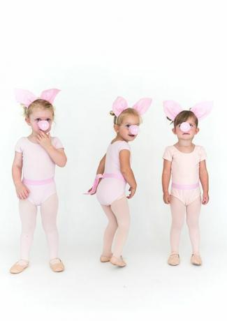 kleine meisjes in roze panty's en rompertjes met varkensoren en varkenssnuiten