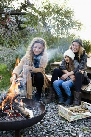 twee vrouwen en een meisje zitten bij de vuurplaats, ontspannen
