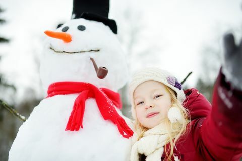 Aanbiddelijk meisje die een sneeuwman in mooi de winterpark bouwen. Schattig kind spelen in een sneeuw.