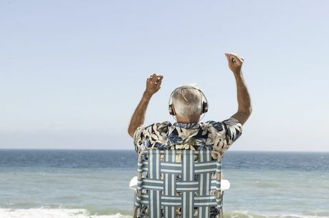 Gelukkig oude man luisteren naar muziek met uitzicht op de zee