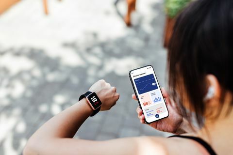 jonge vrouw die fitness-tracker-app gebruikt op smartwatch en smartphone