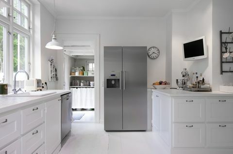 Witte keuken met zilveren rechte koelkast in Hanne Davidsen-huisvernieuwing, Silkesborg, Denemarken.