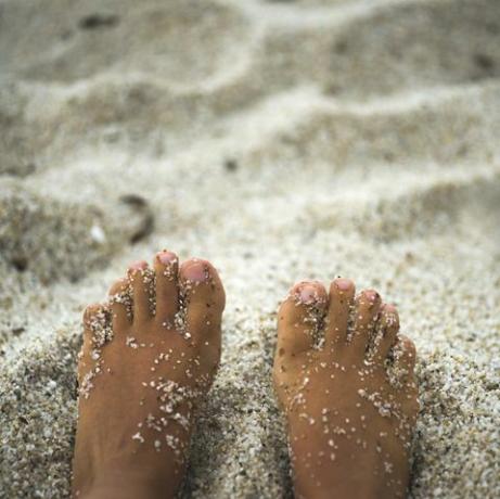 gebruinde vrouw voeten in het zand