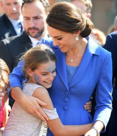 Hertogin van Cambridge omhelst een kind terwijl ze een goed doel bezoekt dat jongeren uit kansarme achtergronden in Berlijn ondersteunt tijdens een officieel koninklijk bezoek aan Duitsland