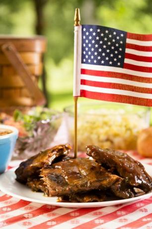 BBQ-ribben gegarneerd met Amerikaanse vlag, bonen, aardappelsalade op een rood en wit tafelkleed