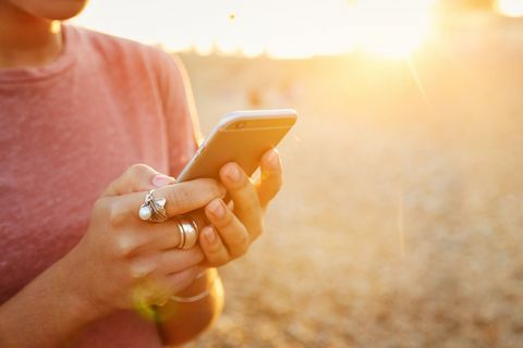 Vrouw die mobiele telefoon op strand houdt