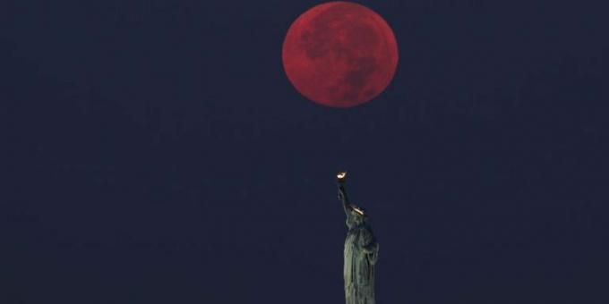volle maan gaat onder achter het vrijheidsbeeld in New York City