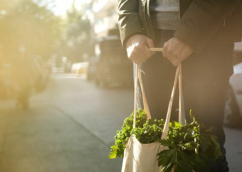 jonge man met herbruikbare boodschappentas van textiel met groene groenten