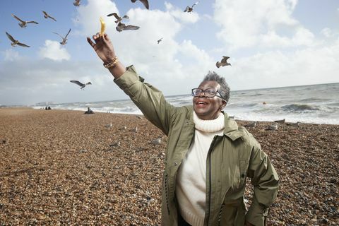 hogere vrouw die frieten aan vogel voedt