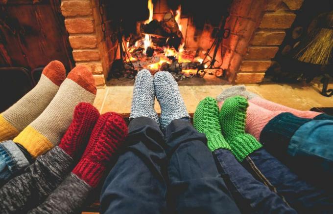 benen weergave van gelukkige familie met warme sokken voor de open haard winter, liefde en gezellig concept focus op grijze wollen sokken in het midden