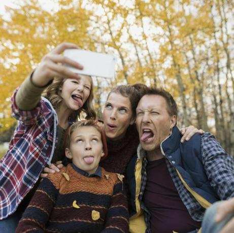 Domme familie die selfie maakt en gezichten maakt in het herfstpark